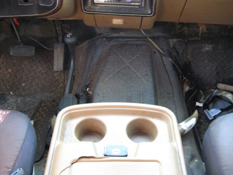 1990 Ford Bronco - The interior of a 1990 Ford Bronco, a center console with cup holders and a floor-mounted shifter.