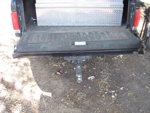 1990 Ford Bronco - Rear view of a pickup truck's open tailgate, showing a toolbox and trailer hitch.