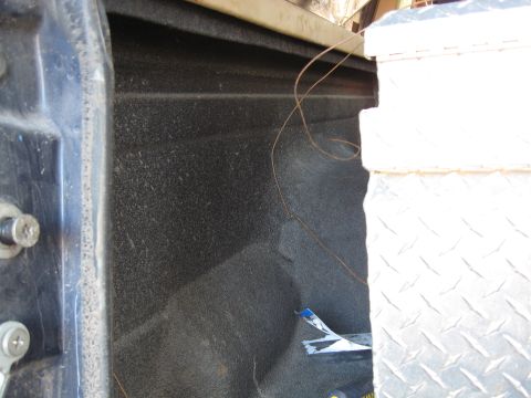 1990 Ford Bronco - The interior of a truck bed shows a textured surface and a metal toolbox.