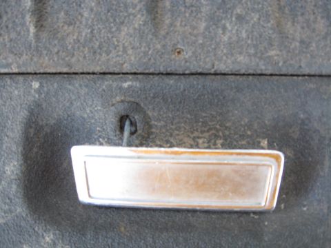 1990 Ford Bronco - Close-up of a vehicle's interior door handle, showing its metallic finish and surrounding textured panel.