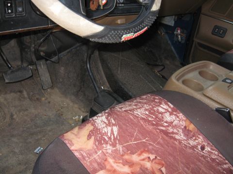 1990 Ford Bronco - Interior view of a vehicle with camouflage seat cover and worn pedals.