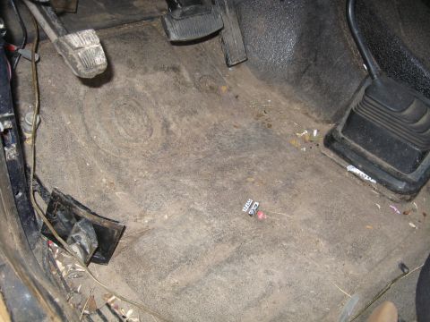 1990 Ford Bronco - The interior floor of the vehicle is dirty and shows wear around the pedals and gear shifter.