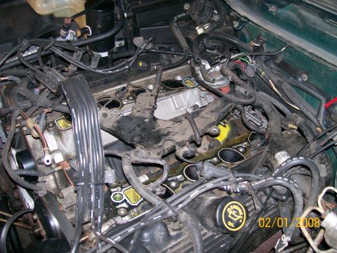 1995 Mercury Grand Marquis - Engine bay view of a V8 with the intake manifold removed, exposing the cylinder heads, valley, and pushrods; a black oil fill cap marked 'E…
