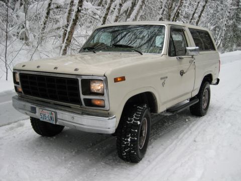 1980 Ford Bronco - A white 1980 Ford Bronco navigates a snowy road, its off-road capability.