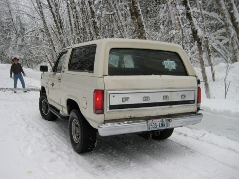 1980 Ford Bronco - White 1980 Ford Bronco in a snowy forest setting with a person in the background.