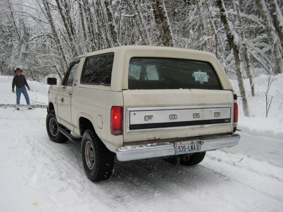 1980 Ford Bronco parked on snowy road, person standing nearby