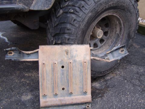 2003 Jeep Wrangler - A transmission pan skid plate is shown removed from a vehicle, with a tire visible in the background.