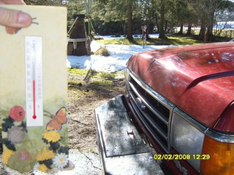 1989 Ford Bronco - A thermometer is held up in front of a red pickup truck with snow on the ground.