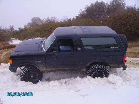 1990 Ford Bronco - A black 1990 Ford Bronco is stuck in the snow on a winter day.