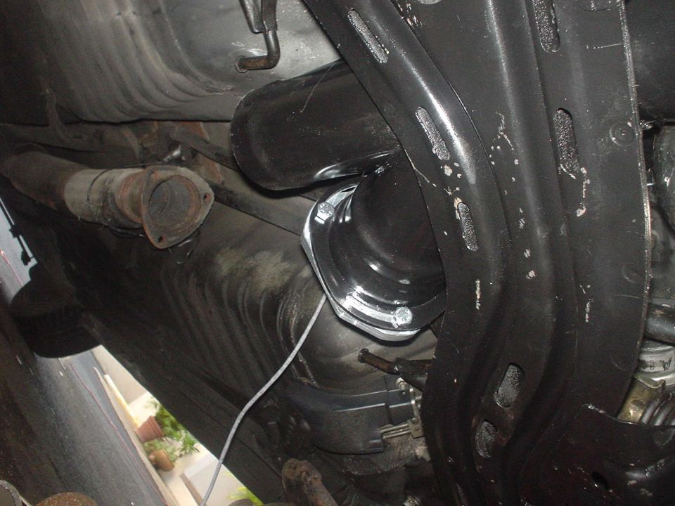 Underbody view of exhaust pipe and suspension parts. A white wire is visible
