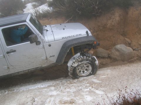 1985 Ford Bronco - Jeep Wrangler Rubicon navigating a snowy and muddy off-road trail.