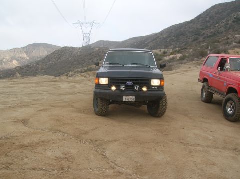 1985 Ford Bronco - A black 1985 Ford Bronco is parked on a dirt road, with a red Bronco visible to the right.