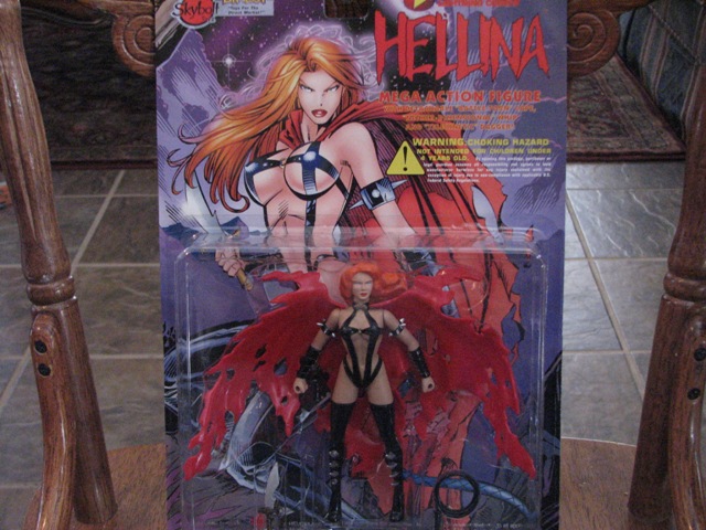 Hellina action figure in blister pack with comic art background. Supermotors.net logo visible