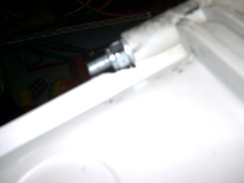 2005 Ford Mustang - A close-up of a bolt against a white surface, with blurred items in the background.