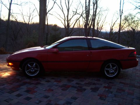 1989 Ford Probe - Red 1989 Ford Probe coupe parked on a brick patio with trees in the background.