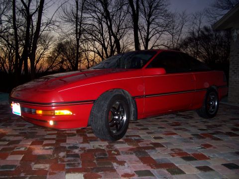 1989 Ford Probe - A red 1989 Ford Probe is seen from a 3/4 front angle on a brick surface with trees in the background.