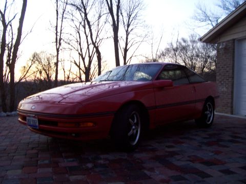 1989 Ford Probe - Red 1989 Ford Probe coupe sits on a brick driveway during sunset.