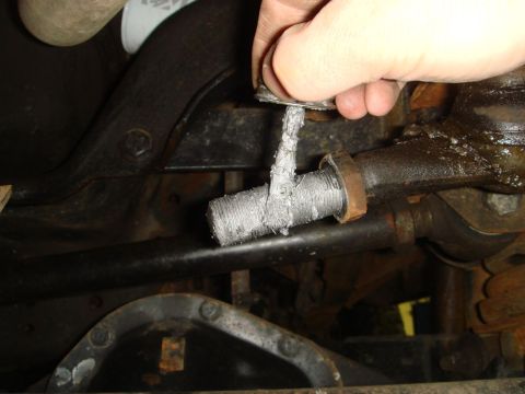 1996 Ford Bronco - Close-up of a drag link with a hand holding a cap, likely during a repair or inspection.