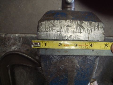 1996 Ford Bronco - A metal part is secured in a vise and measured with a tape measure.