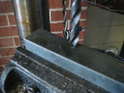 1996 Ford Bronco - A drill bit is about to penetrate a metal workpiece clamped to a drill press.