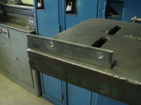 1996 Ford Bronco - A close-up view of a metal bracket attached to a workbench, with blue lockers visible behind it.