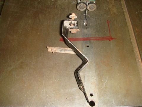 1996 Ford Bronco - Metal bracket with bolts and washers positioned on a bandsaw table.