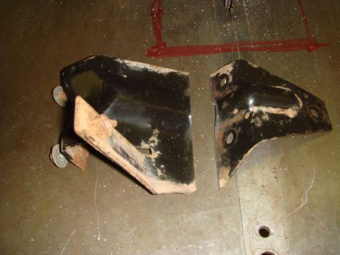 1996 Ford Bronco - Two metal brackets, likely automotive parts, are shown on a textured surface.