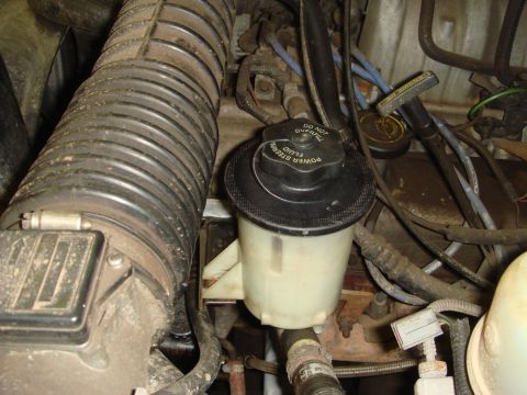 1996 Ford Bronco - Close-up of engine bay components including the power steering fluid reservoir and air intake hose.