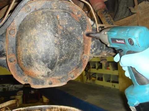 1996 Ford Bronco - Impact wrench is used to remove bolts from the differential cover of a vehicle's rear axle.