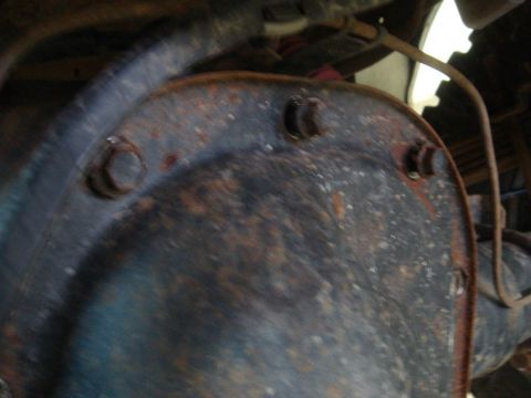 1996 Ford Bronco - A close-up view of a heavily rusted differential cover, showing bolts and surrounding axle components.