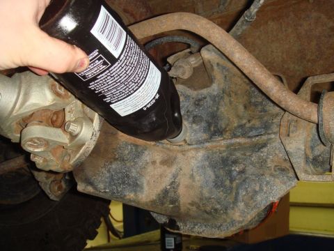 1996 Ford Bronco - Pouring fluid into the rear differential housing of a vehicle.