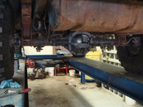 1996 Ford Bronco - The rear differential and axle assembly of a vehicle are shown while it is elevated on a car lift in a workshop.
