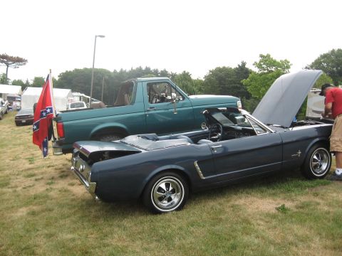1996 Ford Bronco - A green 1996 Ford Bronco is parked next to a dark blue convertible, both on display at an outdoor event.