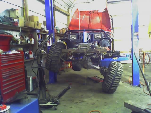 Red 1992 Ford Bronco on a lift, hood up, in a garage with tools
