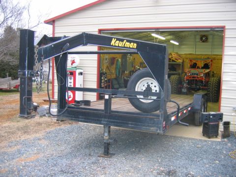 1992 Ford Mustang - Off-road vehicle and trailer parked outside a garage with a vintage gas pump.