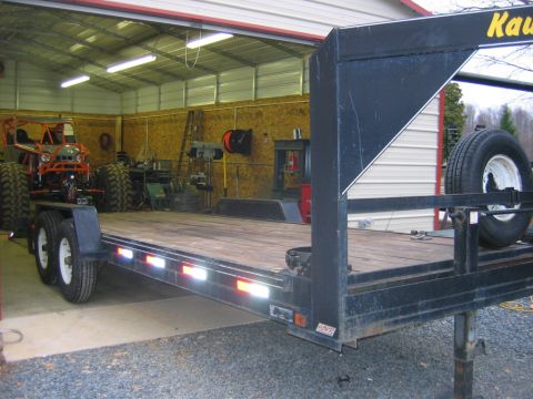 1992 Ford Mustang - A flatbed trailer is loaded with a custom off-road vehicle inside a garage.