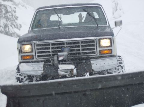 1986 Ford Bronco - A Ford Bronco navigates through a snowy landscape, its headlights illuminating the falling snow.
