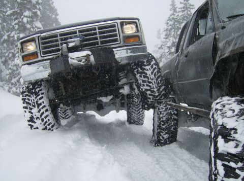 1986 Ford Bronco - A 1986 Ford Bronco equipped with a winch navigates deep snow alongside another vehicle.