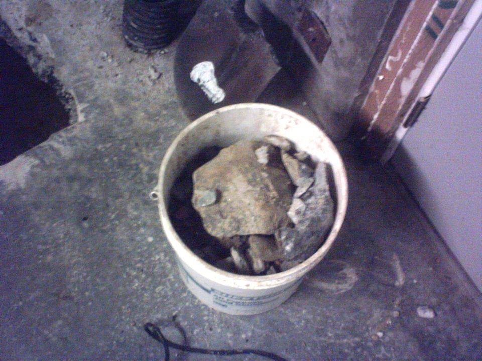 Bucket filled with rocks and debris on a concrete floor