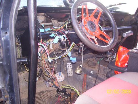 1978 Ford Bronco - Interior view of a vehicle with extensive exposed wiring and an aftermarket steering wheel.