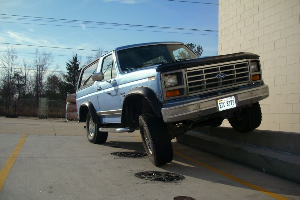 Blue Ford Bronco front three-quarter view parked on a curb