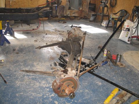 1995 Ford Bronco - Vehicle axle and suspension components are disassembled and laid out on a workshop floor.