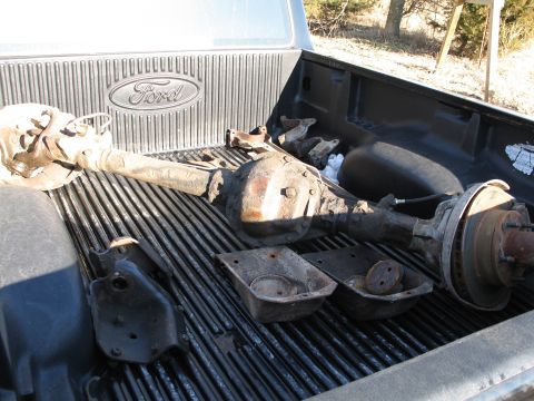 1995 Ford Bronco - Ford rear axle assembly and other parts loaded in the bed of a pickup truck.