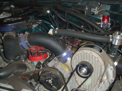 1996 Ford Bronco - Close-up of a Powerdyne supercharger installation on a V8, showing the belt-driven cast blower housing, black charge tubing joined with blu…