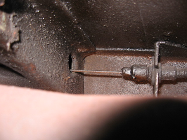 Close-up of a clutch cable mechanism on a dark, greasy surface