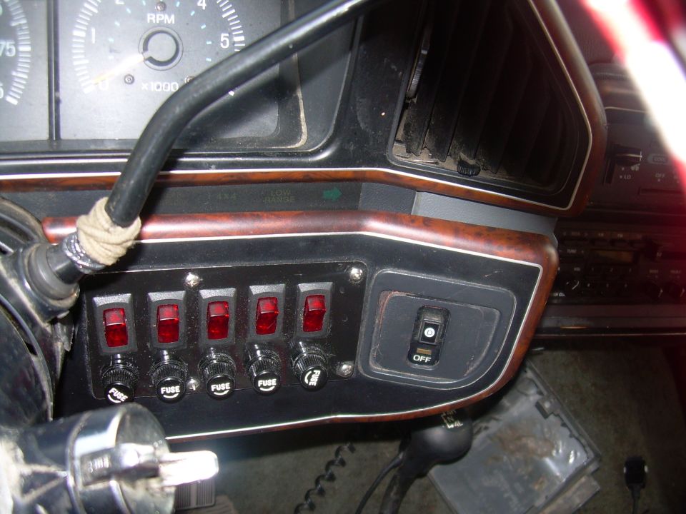 Dashboard interior with red switches, fuse labels, and RPM gauge