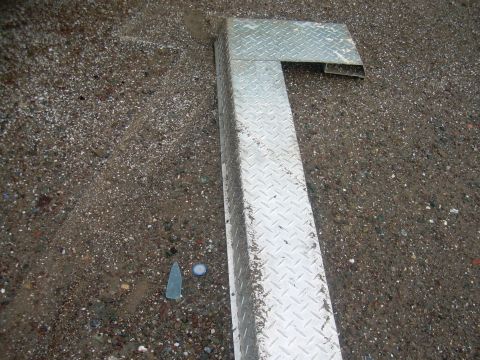 1991 Ford Bronco - A diamond plate metal step is shown resting on a gravel surface. The registry claims it is from a 1991 Ford Bronco, but this is unconfirmed.