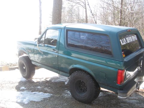 1996 Ford Bronco - A green Ford Bronco is shown from the side, parked on a gravel surface with some snow.