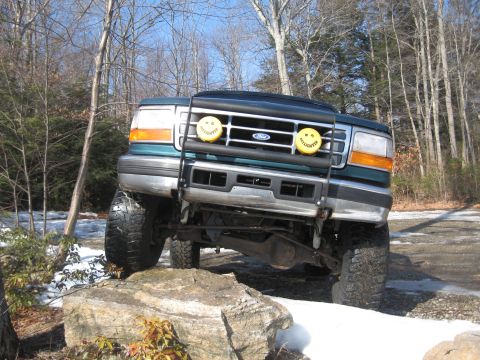 1996 Ford Bronco - Green 1996 Ford Bronco navigating rocky terrain with a bull bar and auxiliary lights.