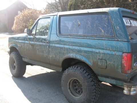 1996 Ford Bronco - This muddy 1996 Ford Bronco is shown from the side, equipped with large off-road tires.